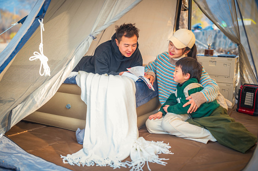 Happy loving family reading a book together In the tent