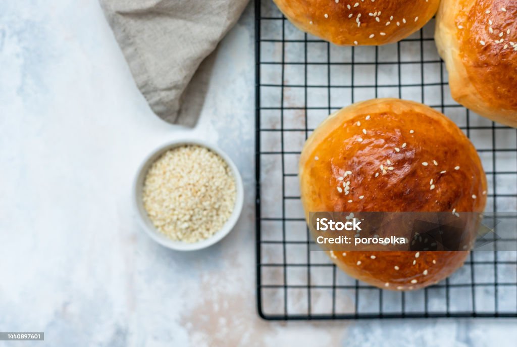 Round buns with sesame seeds, bread rolls. Tasty homemade burger bread with sesame, concrete background. Freshly baked hamburger buns. Top view. Round buns with sesame seeds, bread rolls. Tasty homemade burger bread with sesame, concrete background. Freshly baked hamburger buns. Bun - Bread Stock Photo