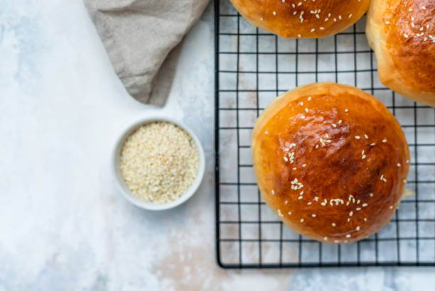 Round buns with sesame seeds, bread rolls. Tasty homemade burger bread with sesame, concrete background. Freshly baked hamburger buns. Top view. Round buns with sesame seeds, bread rolls. Tasty homemade burger bread with sesame, concrete background. Freshly baked hamburger buns. sweet bun stock pictures, royalty-free photos & images