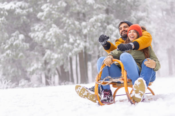 istock Couple sitting on sled and sliding down the hill while on winter vacation 1440897758