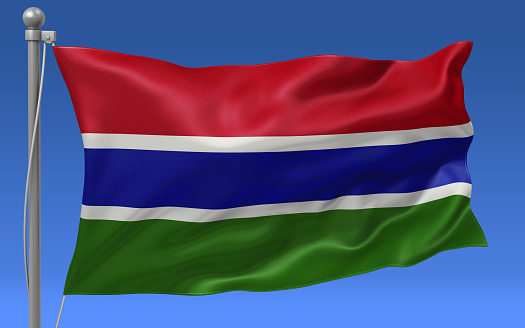 Gambia flag waving on the flagpole on a sky background