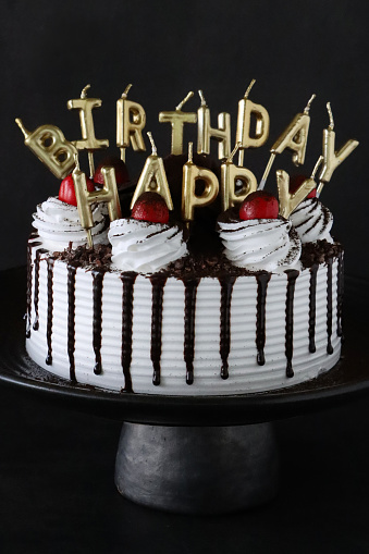 Stock photo showing an elevated view of a homemade, luxury, Black Forest gateau cake with candles spelling \