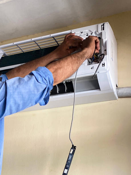 istock Close-up image of unrecognisable handyman checking electrics of air conditioning extractor unit in apartment domestic room, health and safety concept 1440907323
