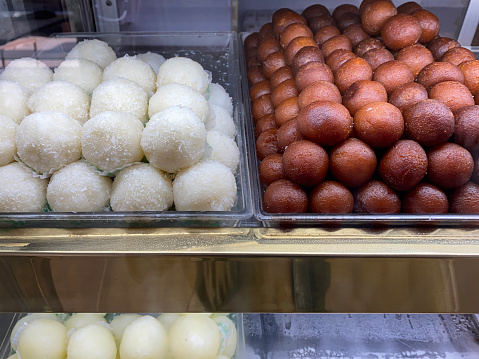 Stock photo showing close-up view of trays containing Indian sweets in a sweet shop. These candy balls are called rasgulla made from chenna (Indian cottage cheese) and Gulab jamun the national dessert of India.