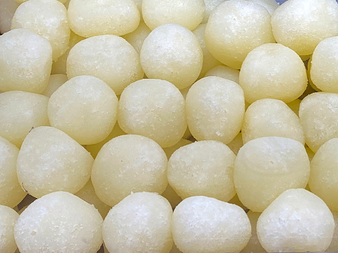 Stock photo showing elevated view of tray containing Indian dessert in a sweet shop. These candy balls are called rasgulla and are made from chenna (Indian cottage cheese) solids kneaded into small balls and then boiled in a sugar syrup (water, sugar and cardamom).