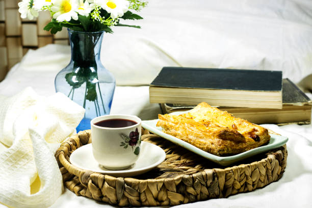 breakfast tray : homemade puffed pastry apple tart with ice cream and daisy flowers and cup of coffee on hotel bed room with books - tart dessert tray bakery imagens e fotografias de stock