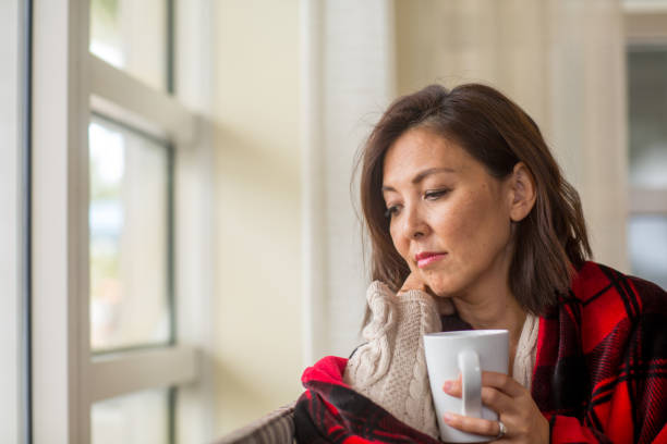 istock Mature woman looking out the window feeling sad. 1440912596