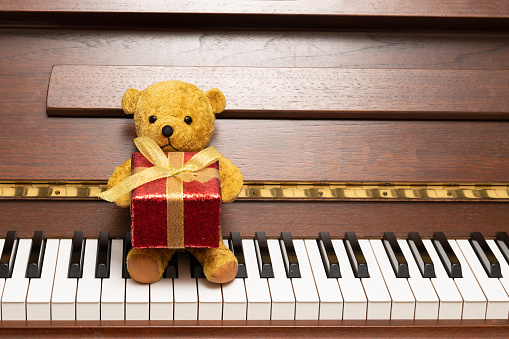 Teddy bear with a present sitting at the piano