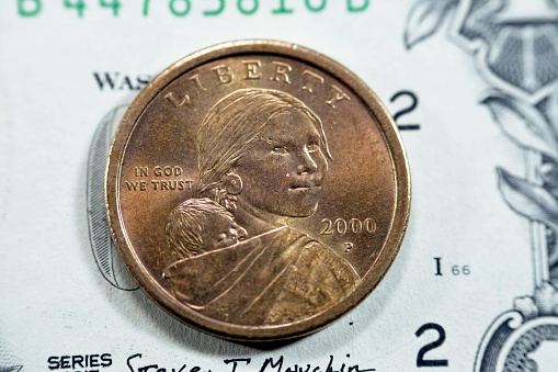 The golden Sacagawea dollar series 2000, American 1 $ one dollar coin series 2000 features a profile of Sacagawea with her child, Jean Baptiste Charbonneau, vintage retro old USA coin on a USD bill, selective focus