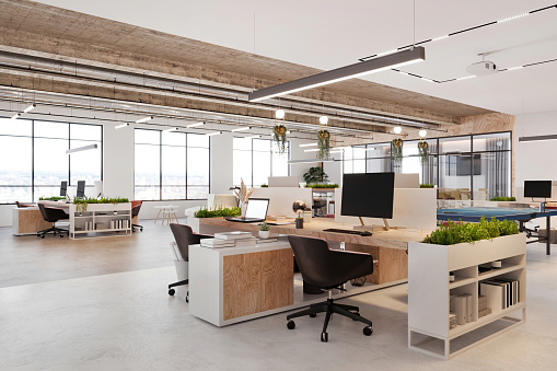 Modern open plan office space interior. Desk, laptop,  computers, armchair, plant, concrete floor and ceiling, and large windows in the background. Template for copy space. Render.