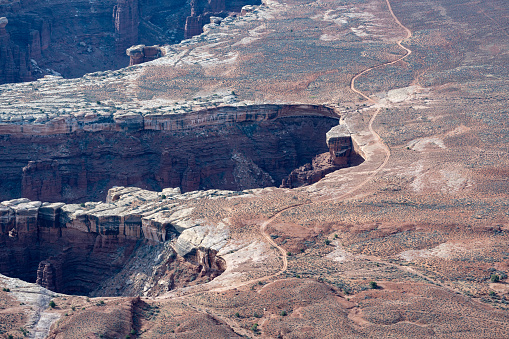 Aerial view overlooking gravel roads, deep canyons, plain deserts and mountain ranges in Canyonlands National Park, Utah, USA.