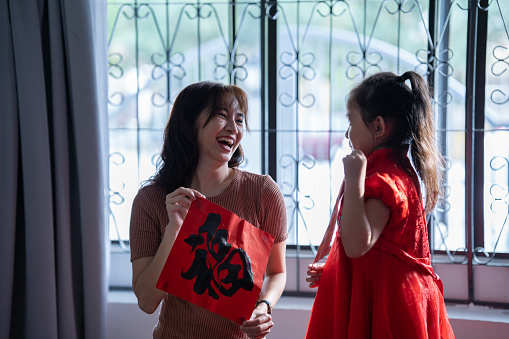 Mother teach daughter to write chinese calligraphy for the preparation of new year decorations