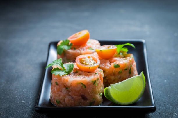 istock Fresh and raw salmon tartare with cherry tomatoes and lime. 1440921448