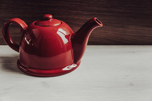 Red teapot on wooden background