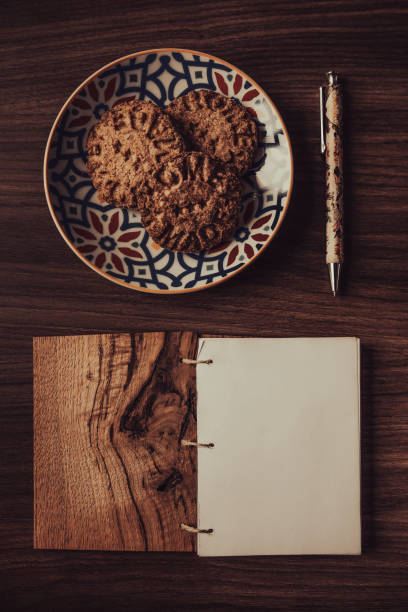 Blank diary page with pen and homemade biscuits on wooden background