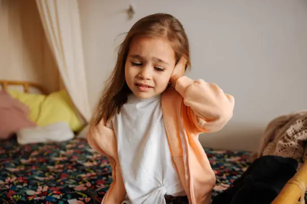 Little girl sick at home, having a severe ear inflammation and an earache