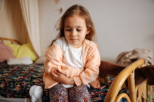 Photo of young girl having stomach pain in the house. Healthcare and illness concept.