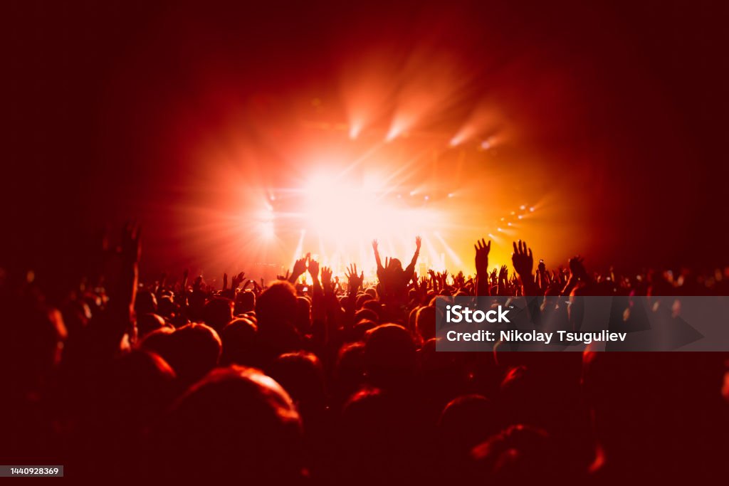 A crowded concert hall with scene stage in red lights, rock show performance, with people silhouette, colourful confetti explosion fired on dance floor air during a concert festival A crowded concert hall with scene stage in red lights, rock show performance, with people silhouette, colourful confetti explosion fired on dance floor during a concert festival Party - Social Event Stock Photo