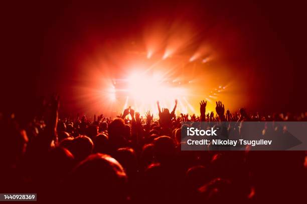A Crowded Concert Hall With Scene Stage In Red Lights Rock Show Performance With People Silhouette Colourful Confetti Explosion Fired On Dance Floor Air During A Concert Festival Stock Photo - Download Image Now