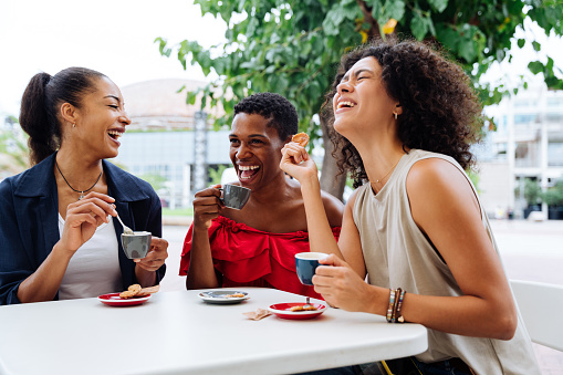 Happy beautiful hispanic south american and black women meeting outdoors and having fun - Black adult females friends spending time together sitting in a bar cafè