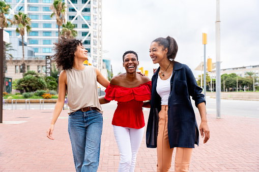 Happy beautiful hispanic south american and black women meeting outdoors and having fun - Black adult females friends spending time together and walking in the city for shopping