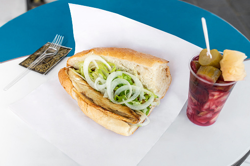 A traditional Istanbul fast food served with bonito, fried onions, lettuce and bread. Pickles served in plastic cups. cucumber, cabbage, turnip.