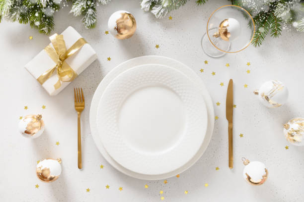 istock Beautiful Christmas festive table setting with white plate, golden balls on white. 1440938008