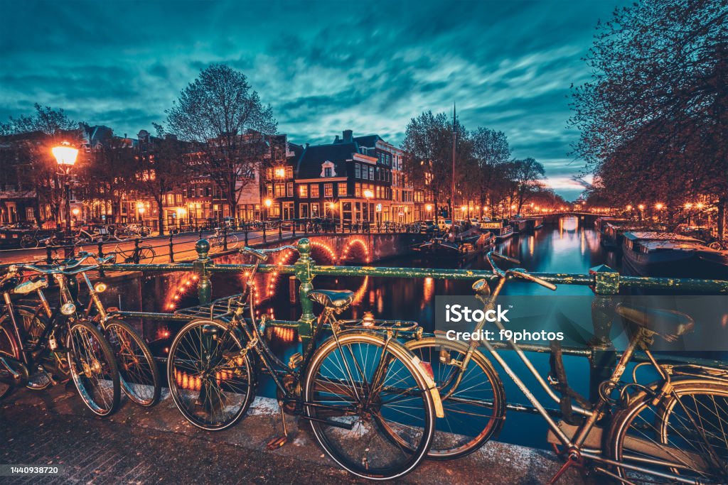 Amterdam canal, bridge and medieval houses in the evening Night view of Amterdam cityscape with canal, bridge with bicycles and medieval houses in the evening twilight illuminated. Amsterdam, Netherlands Amsterdam Stock Photo