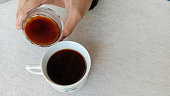 Photo of a person enjoying a cup of black coffee on a wooden table