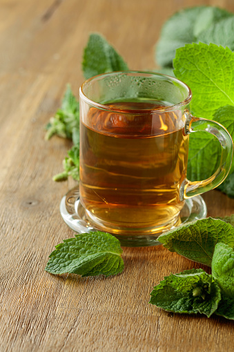 Mint tea in glass on a wooden table.