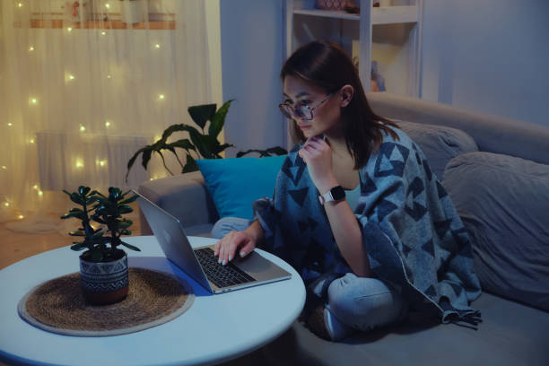 istock Tired focused woman using laptop at night while working overtime against christmas lights background 1440941589