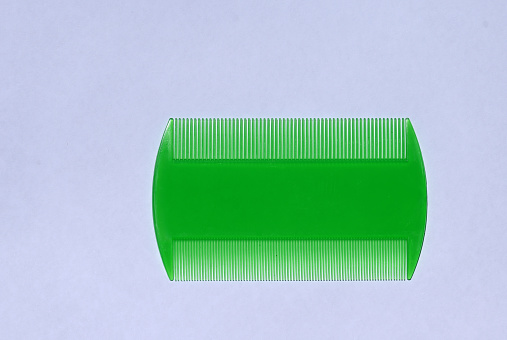 Green plastic head lice or nit comb