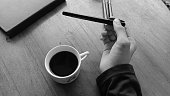 Photo of a person enjoying a cup of black coffee on a wooden table