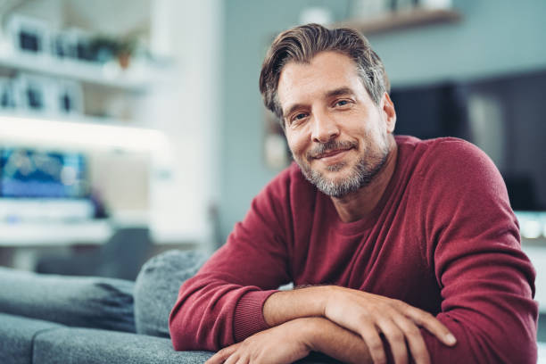 Smiling middle aged man enjoying relaxing time at home stock photo