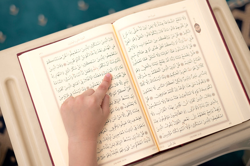 The child who goes to the Quran course and wears the fez learns Arabic from the Quran book in the mosque. The mosque teacher teaches the child to read the Quran.