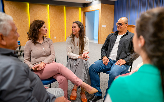 Group of male and female colleagues sitting in circle having a meeting at startup office