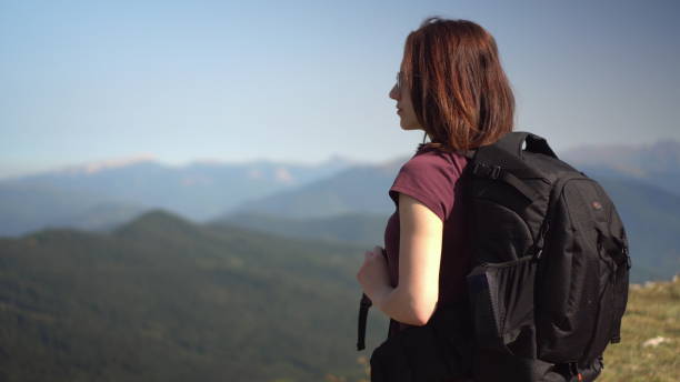 istock Young woman in glasses with a backpack looks at the mountain range. 1440951046