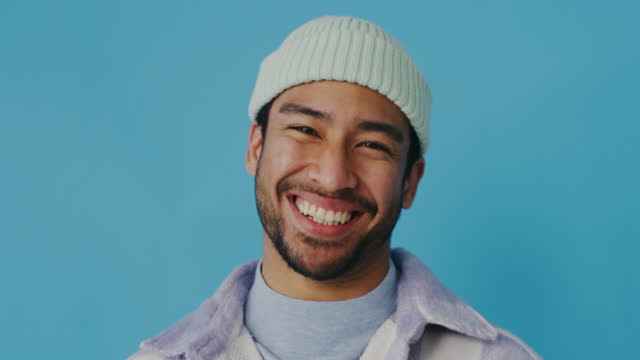Closeup portrait of asian man isolated against a blue background in the studio with copyspace. Face of handsome model laughing at a joke cropped. Headshot of cheerful man making facial expression