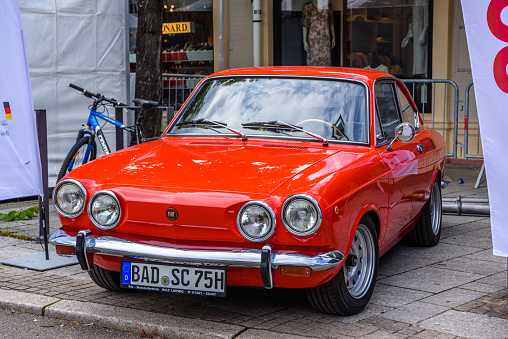 Baden-Baden, Germany - 14 July 2019: red Fiat 850 Sport Coupe from 1971 1964 1973 is parked in Kurpark in Baden-Baden at the exhibition of old cars \