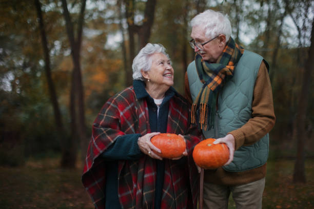 istock Senior couple with pumpkins in autumn forest. 1440953955