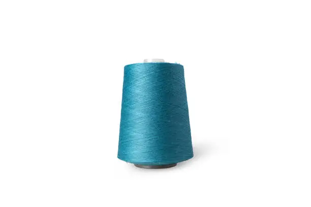 Photo of Spool of sewing thread isolated on white background. Blue green thread used by factories in the clothing industry.