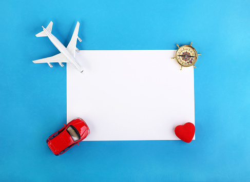 Travel concept with  miniature plane,car,compass,and heart on note paper