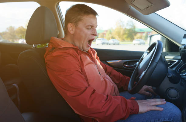 istock Tired driver man wants to sleep, yawns, opens his mouth. 1440959981