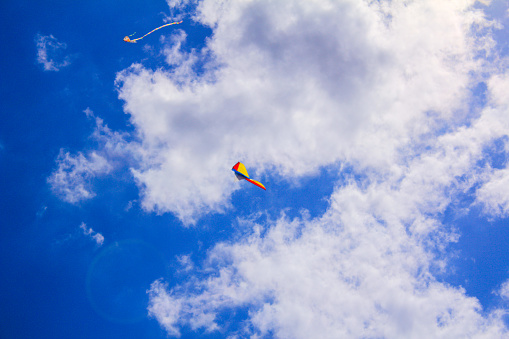 A flying kite in the clear blue sky with clouds