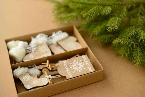 istock Christmas or New Year background with Christmas tree branches, cardboard box with decorative wooden toys - skis, sleds, skates, mittens, hat, top view 1440962100