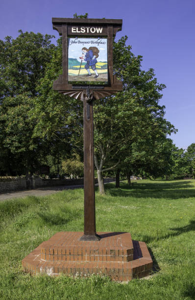 Elstow village sign, the birthplace of John Bunyan Bedford, United Kingdom – June 14, 2021: Elstow village sign, the birthplace of John Bunyan. The sign has a different image on each side and stands by the Moot Hall. book title stock pictures, royalty-free photos & images