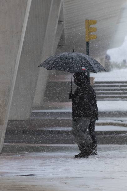 istock People walking down the street with an umbrella while it is snowing 1440965041