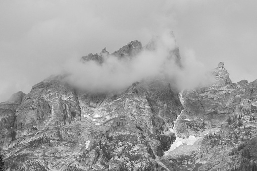 A grayscale shot of clouds above rocky mountains
