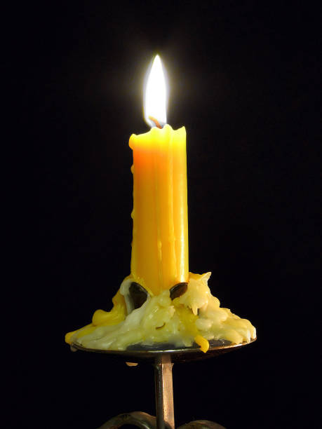 istock Partly melted candle burning on a black background 1440967285