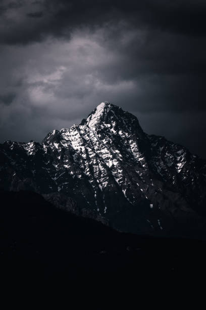 istock Vertical shot of rocky mountains covered in the snow under a dark cloudy sky 1440967430
